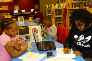 deberes (1) Imagen de niños en la biblioteca en escritorios recibiendo ayuda con su tareas