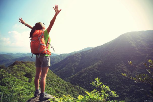 young woman hiker Woman hiker at the top of a mountain arms extended to enjoy the view