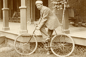 02 - A man identified as 'Lou Bailey,' who rode a Pierce-Arrow bike to Albany, just outside the house on Mansion Street. - LH Collections