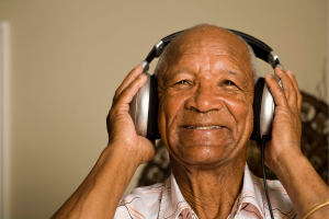 Black senior citizen listening to music on headphones while smiling