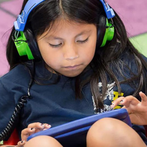 Child with headphones and playing with a tablet device.